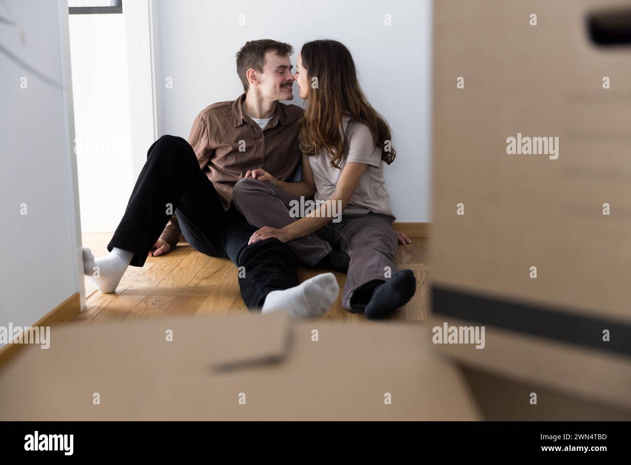 Affectionate multiracial couple kissing each other while sitting at home Stock Photo