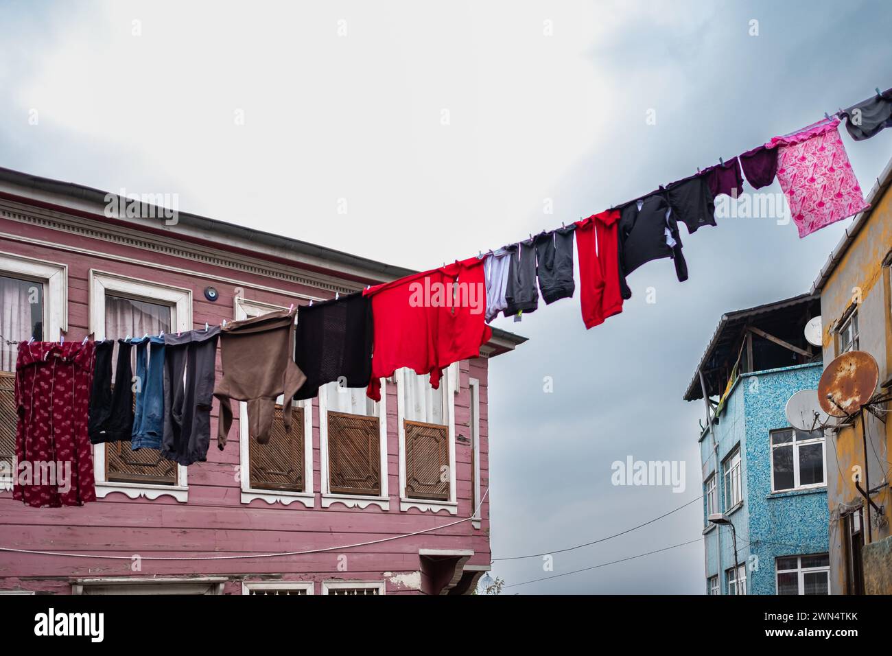 Laundry hanging on a clothes line in old city street. Hanging Laundry. Washed clothes on lines between buildings. Drying clothes hanging outside. Poor Stock Photo