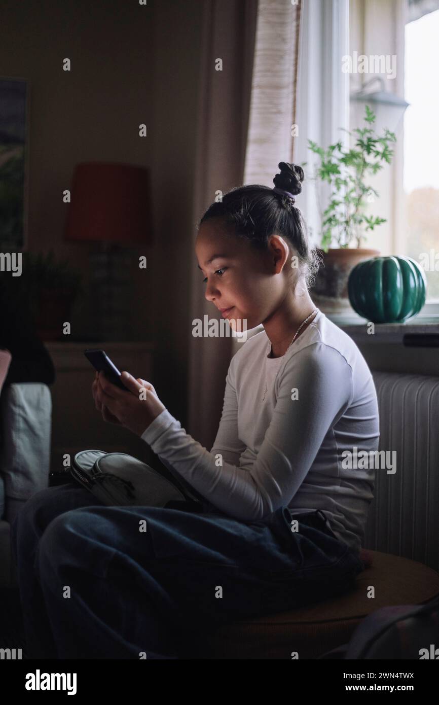 Girl using smart phone while sitting at home Stock Photo