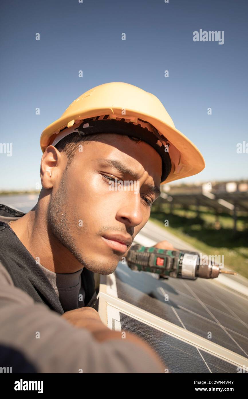 Focused male engineer wearing hardhat and examining solar panels at ...