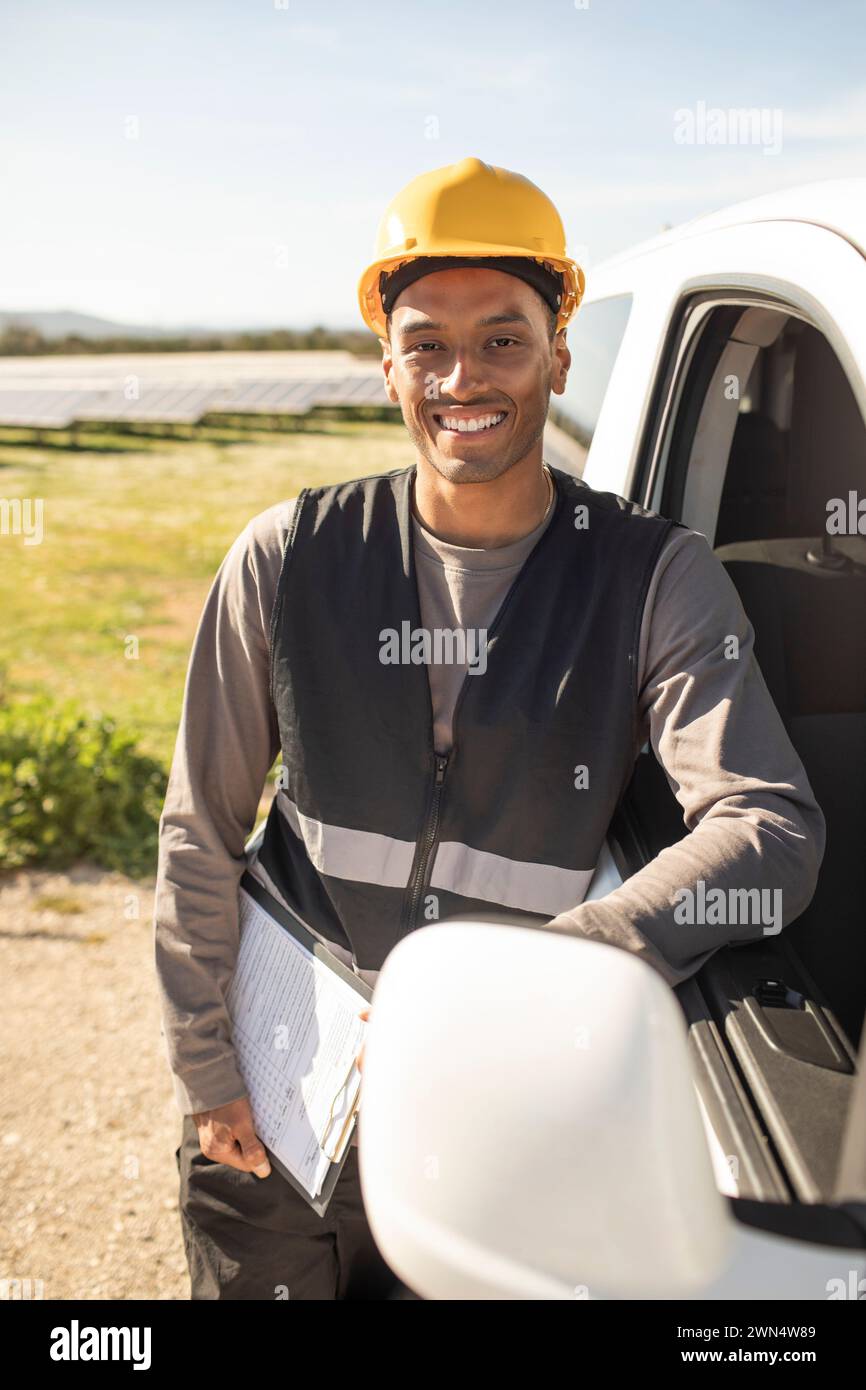 Portrait of confident male engineer holding clipboard while leaning on van door at power station Stock Photo