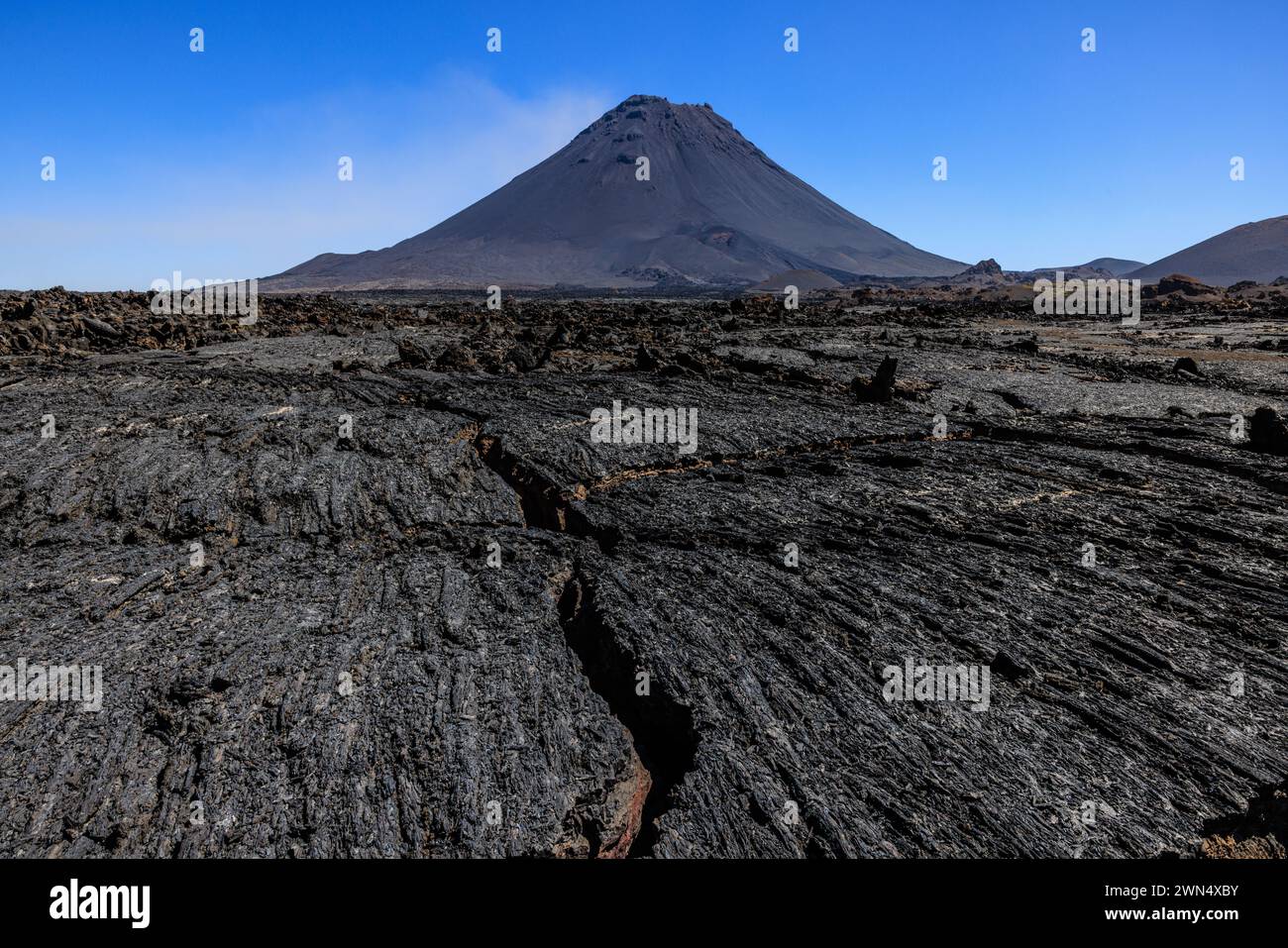 a flat expanse of ropy pahoehoe lava in the caldera of fogo island in front of the classic volcanic peak of pico do fogo on a clear sunny day Stock Photo