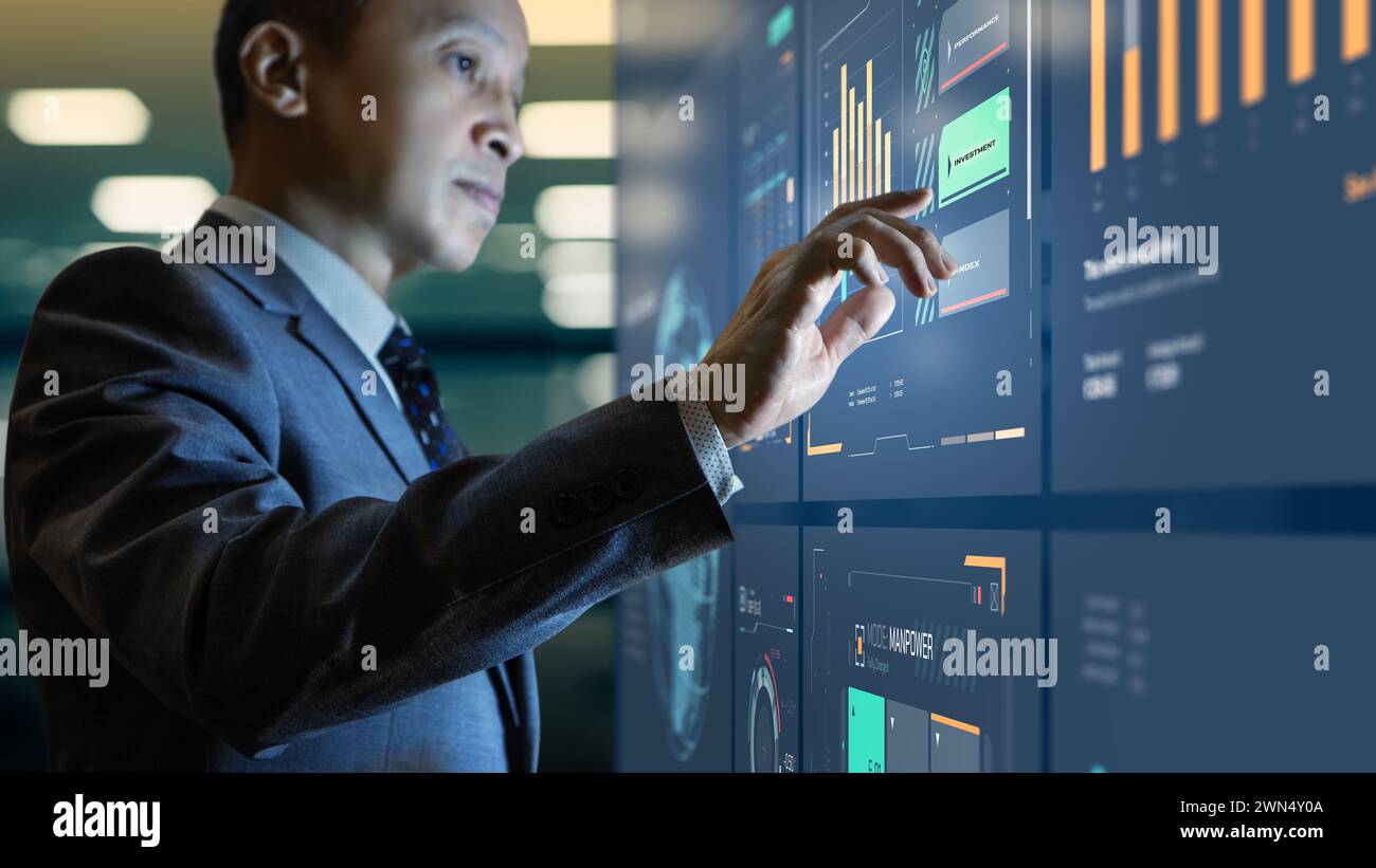 Asian businessman interacting with modern business information dashboard analysing a return on investment Stock Photo
