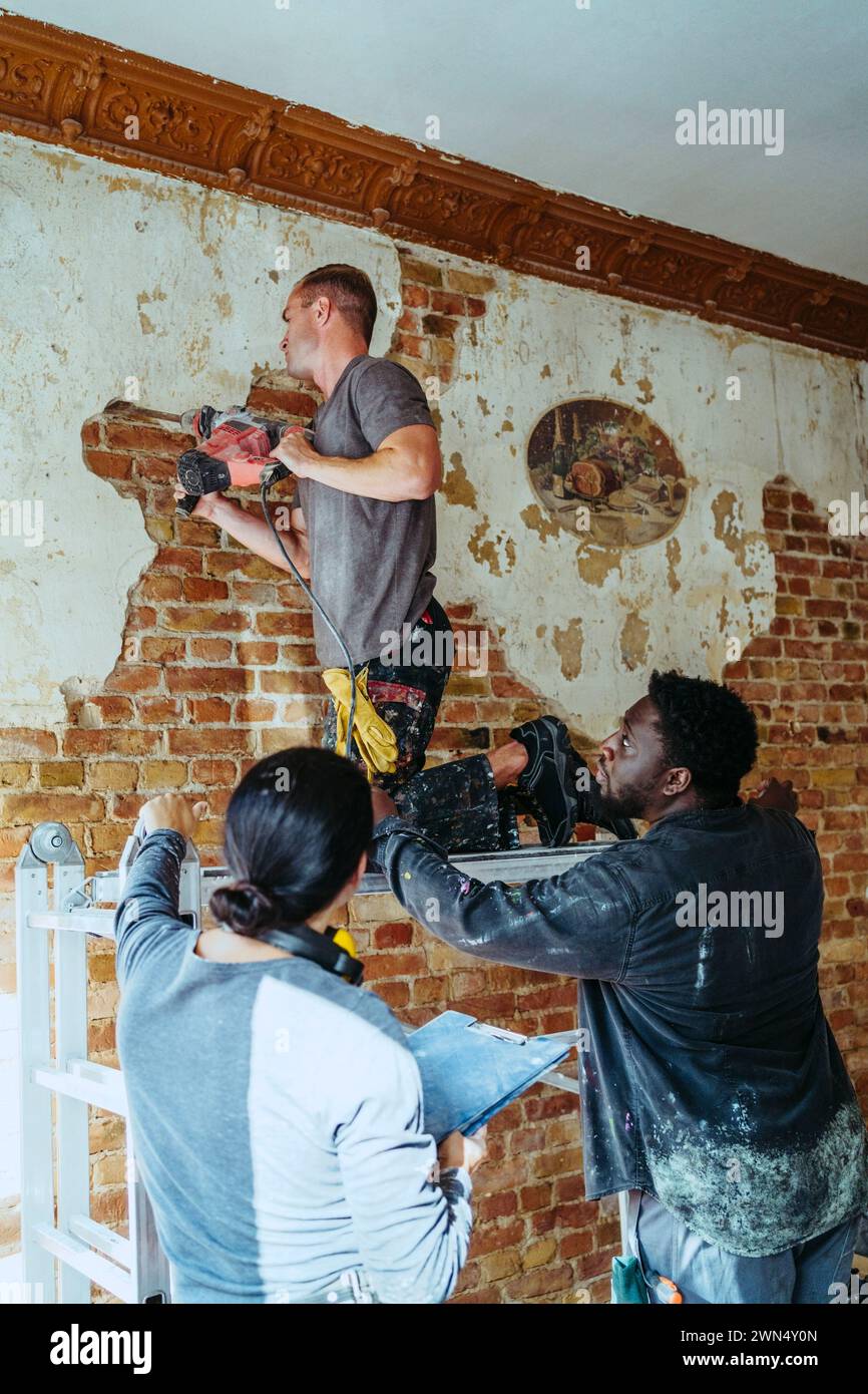 Female construction manager assisting workers in working at site Stock Photo