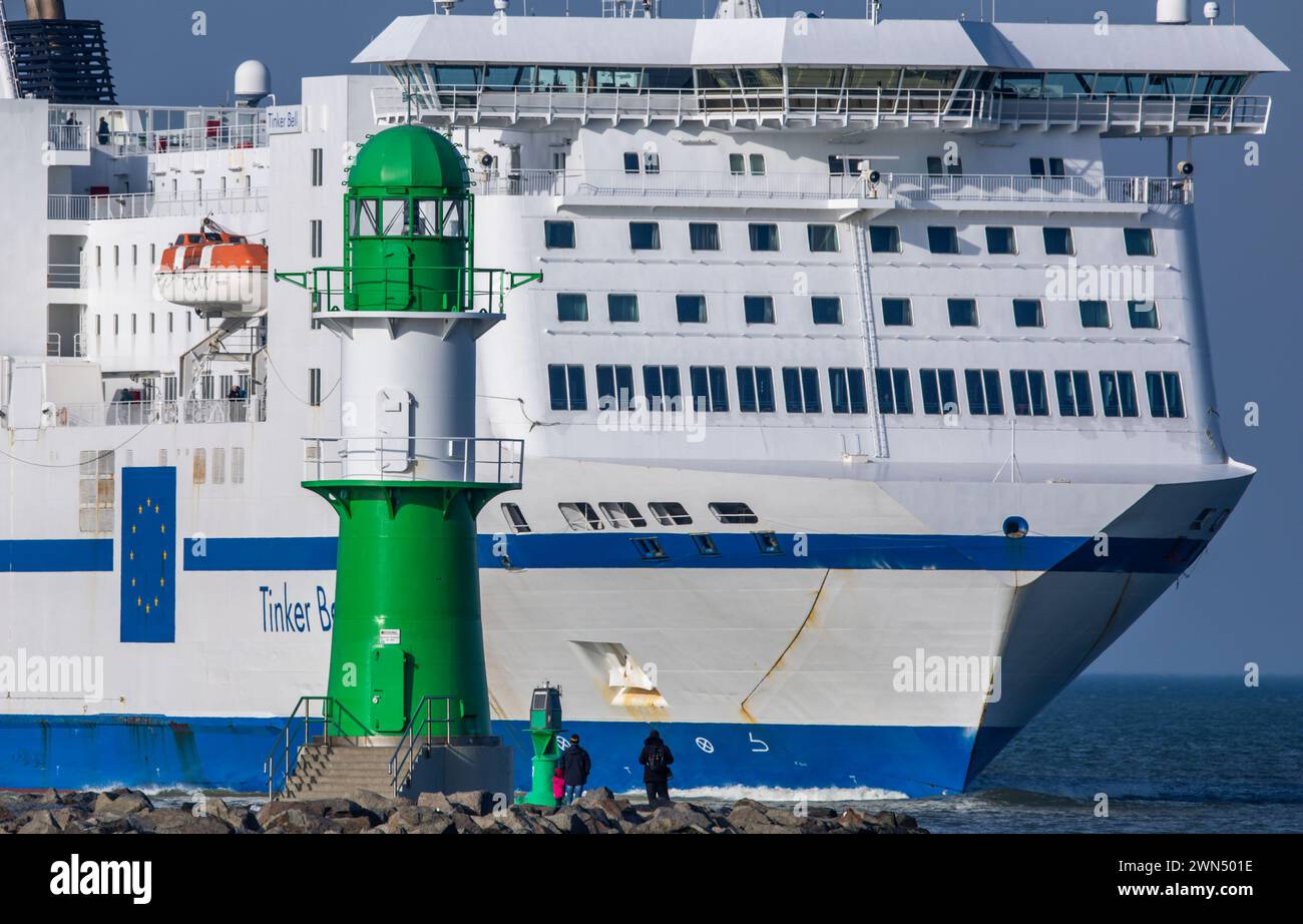 Rostock, Germany. 29th Feb, 2024. Walkers watch from the pier as the TT-Line ferry 'Tinker Bell' arrives. Sunny and with mild temperatures above ten degrees, the last day of February in northern Germany is at its best. Credit: Jens Büttner/dpa/Alamy Live News Stock Photo