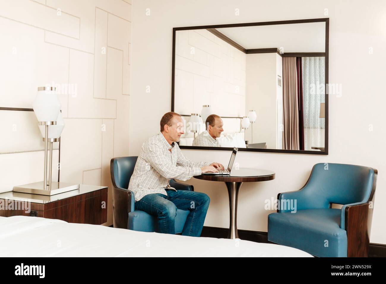 older senior man working on his computer in a hotel room Stock Photo