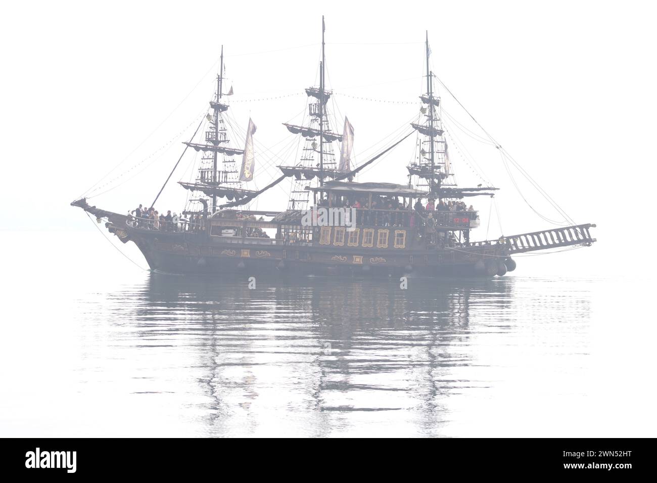 Ghostly voyage. Pirate ship tourist attraction cruising in the misty aegean sea. Stock Photo