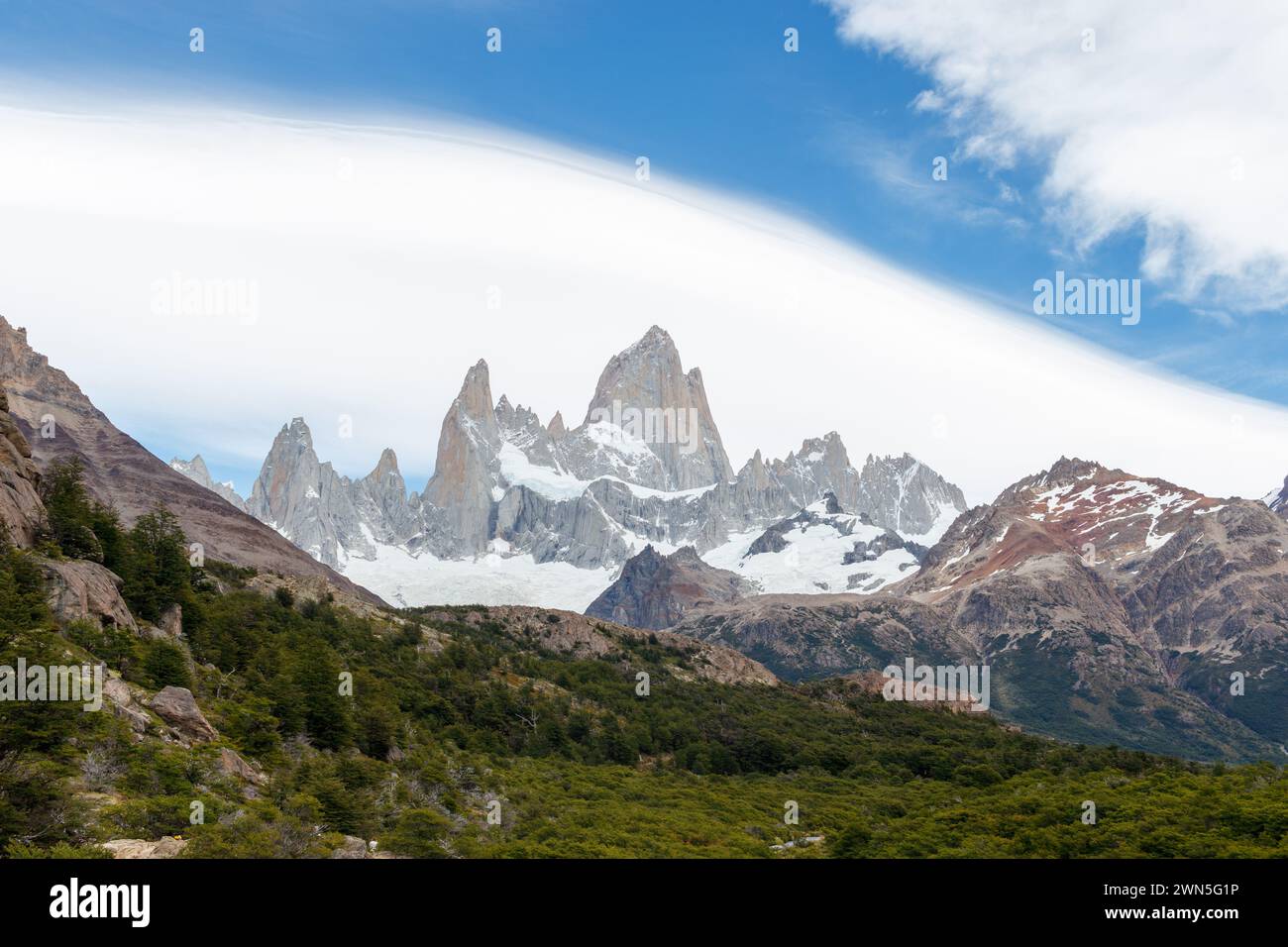 Mountain range Fitz Roy on a sunny day with blue sky and cool clouds. It is a mountain in Patagonia, on the border between Argentina and Chile. Stock Photo
