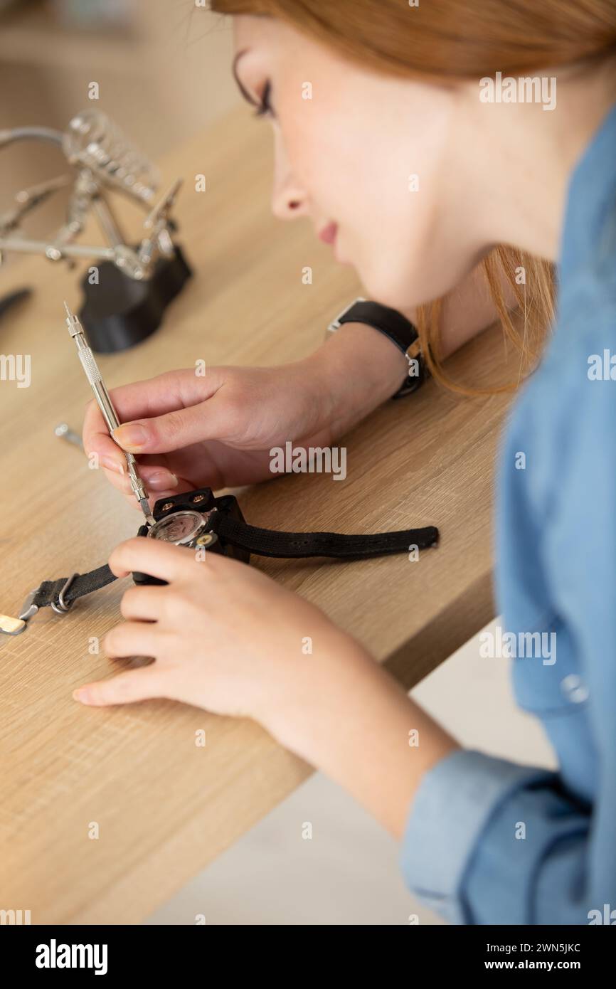 a female is holding tweezers to repair vintage clocks Stock Photo