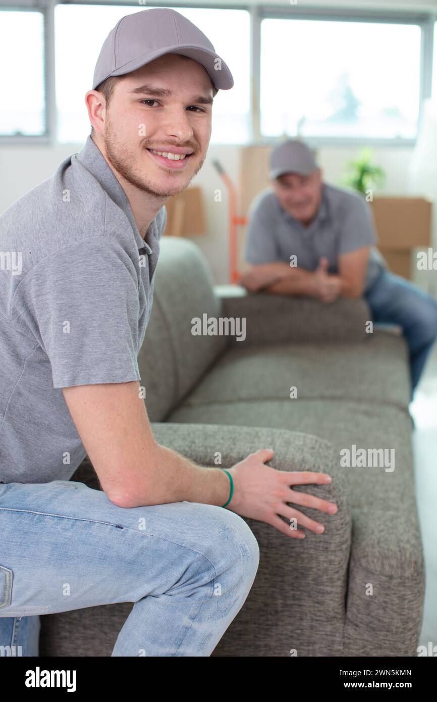 removals men carrying sofa and showing thumbs-up Stock Photo