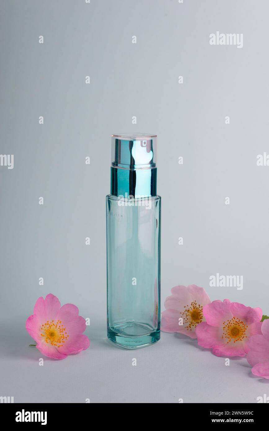 glass bottle of cosmetics with spring flowers on a blue background. Stock Photo