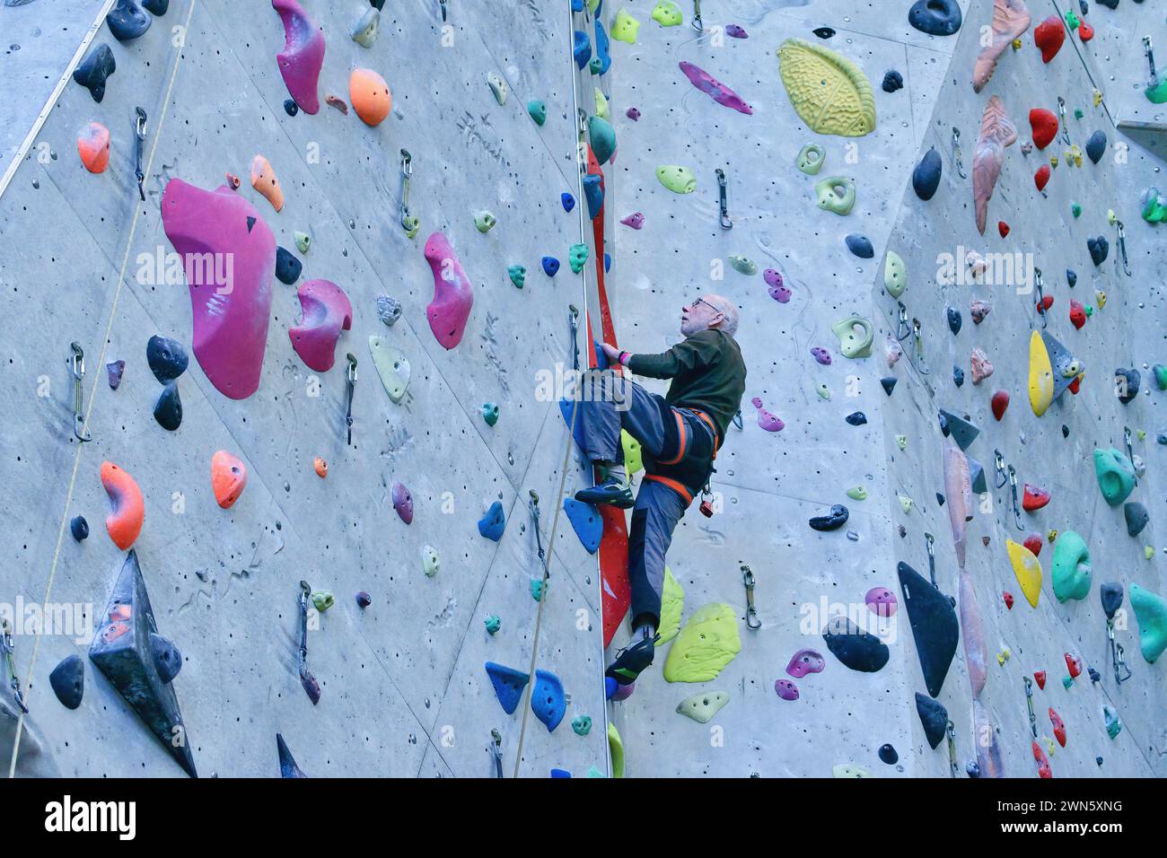 Older climber belaying a partner as they climb Stock Photo Alamy