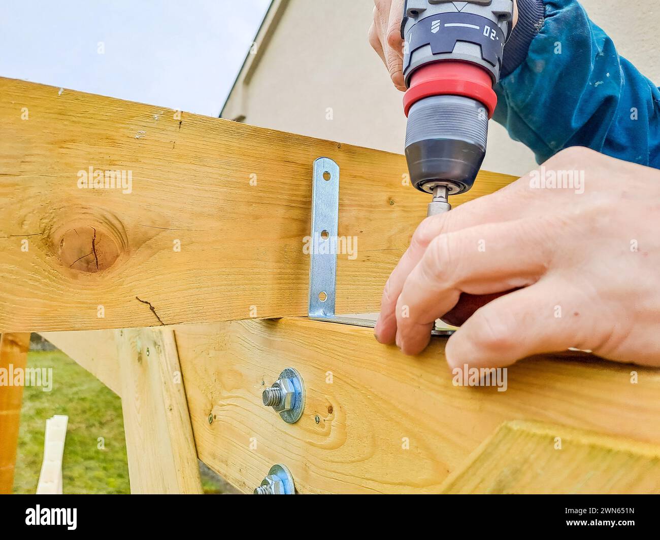 Worker using drill working on construction of wood frame house, gazebo ...