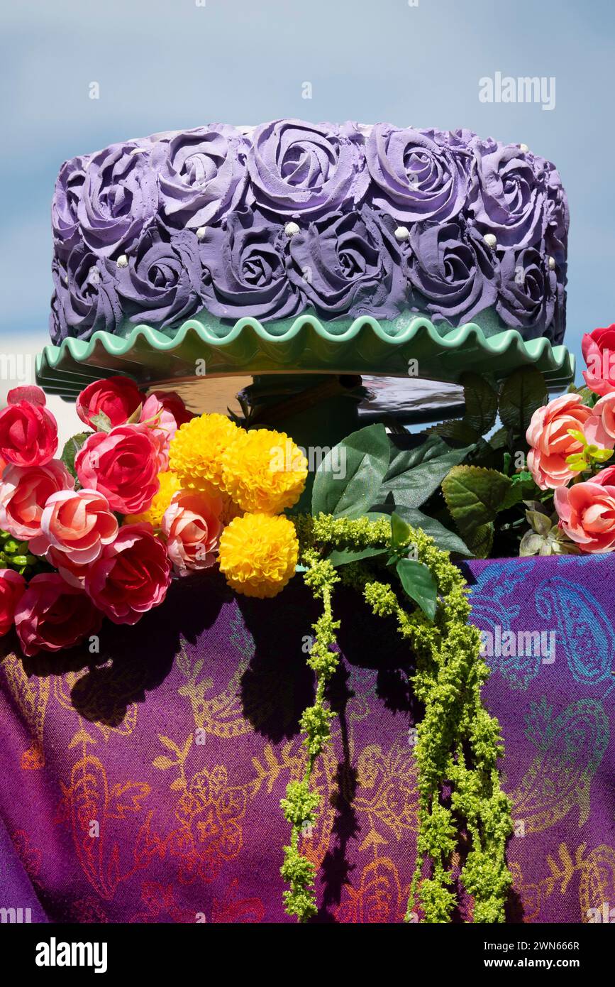 An outdoor display of a fancily designed purple fade frosting on cake with vibrant and colorful designs for confectionery treats at art fair booth Stock Photo