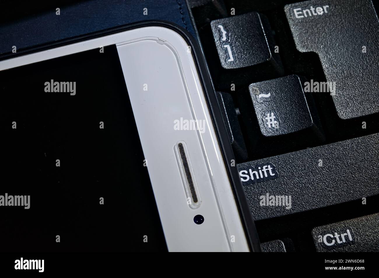 Close-up of a smartphone and computer keyboard keys Stock Photo