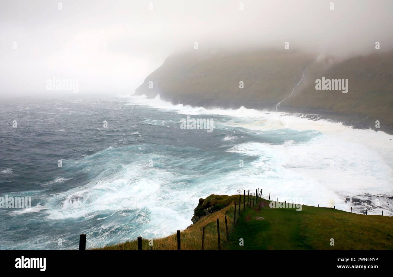 Waves crashing at the steep cliffs coast of the Faroe islands Stock Photo