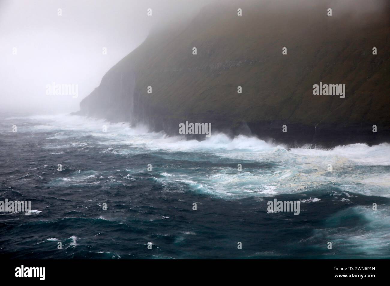Waves crashing at the steep cliffs coast of the Faroe islands Stock Photo