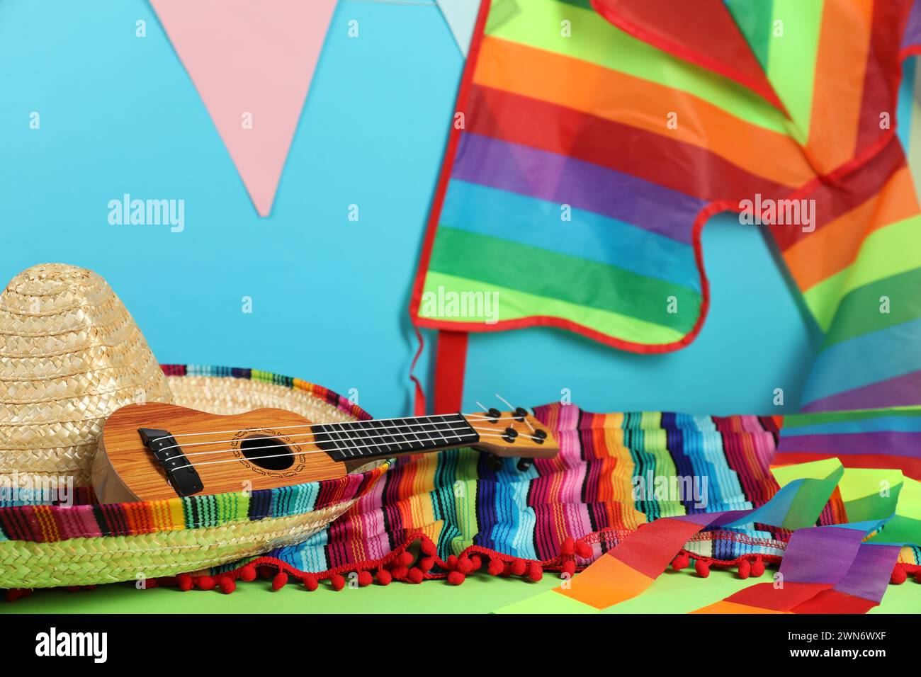 Mexican sombrero hat, poncho and ukulele on green table Stock Photo
