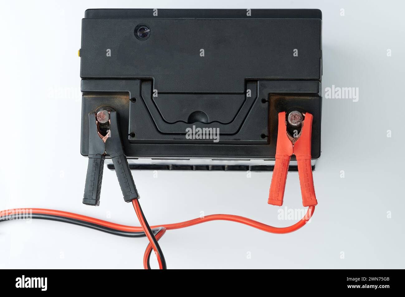Charging black car battery with wire plugs above top view isolated Stock Photo