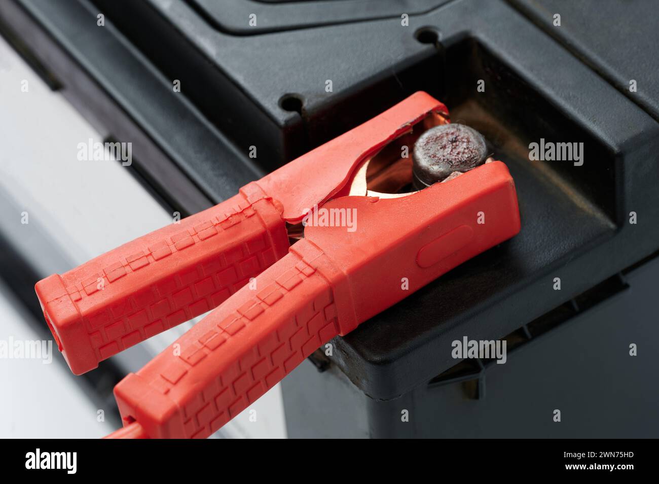 Repair used car battery theme. Red jumper on battery connector close up view Stock Photo