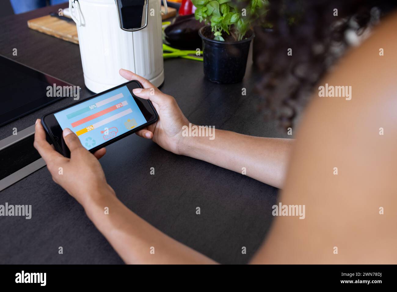 Young biracial woman uses a tablet showing a smart home app at a modern ...