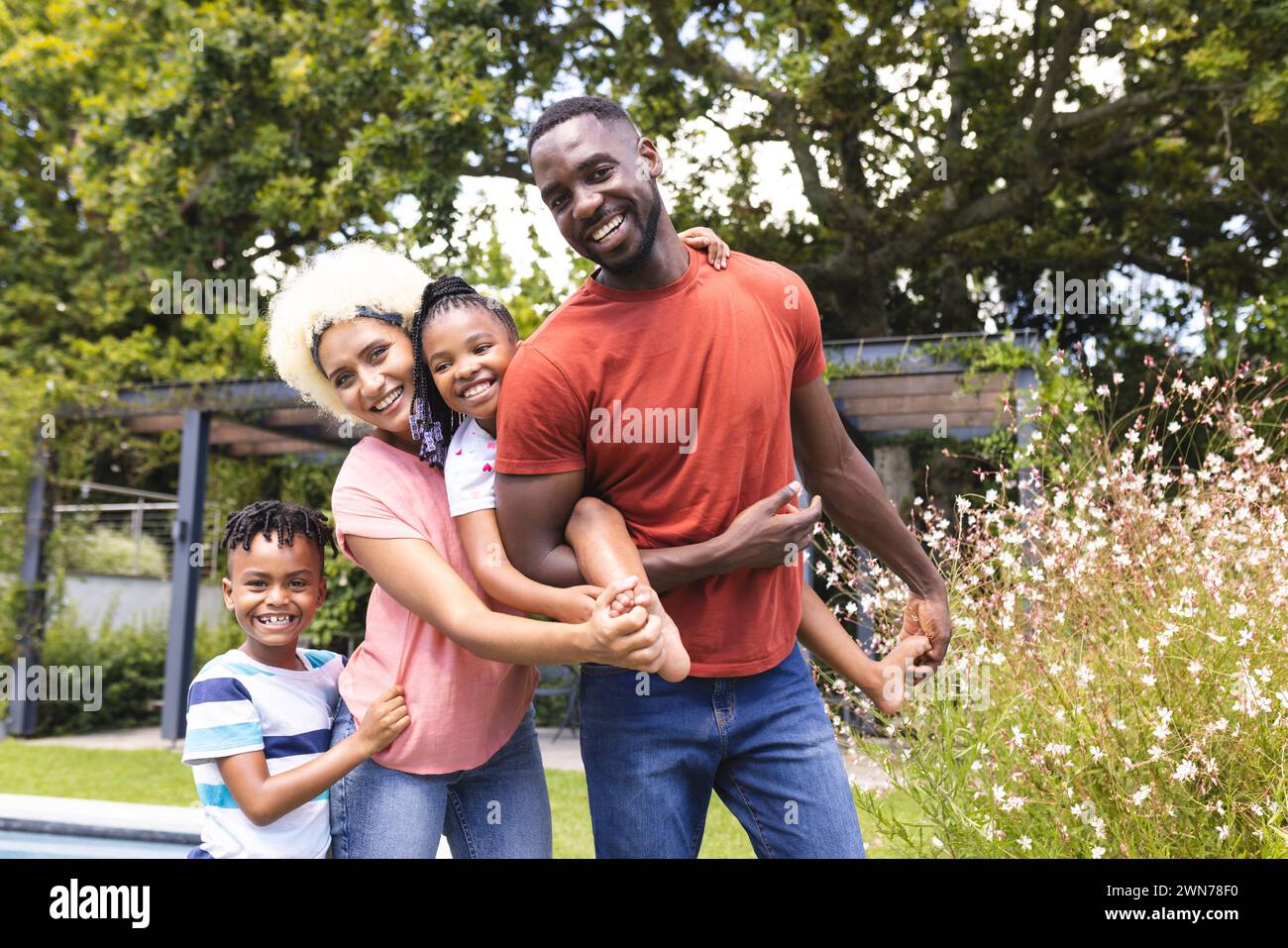 African American man and young biracial woman with their daughter and son are smiling outdoors Stock Photo
