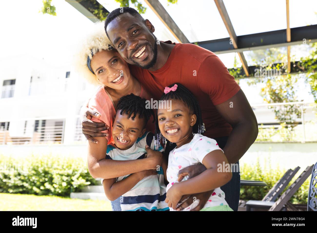 African American man and biracial woman embrace a boy and a girl, all smiling Stock Photo