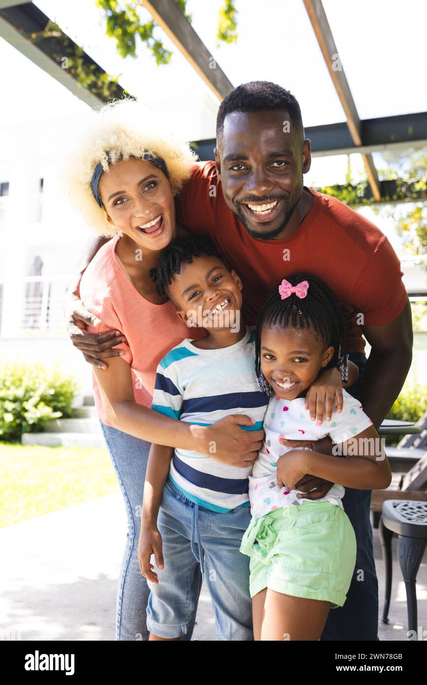African American man with a young biracial woman and two children, smiling outdoors Stock Photo