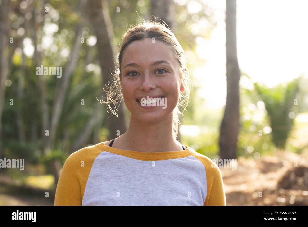 Young Caucasian woman smiles brightly, standing outdoors on a hike Stock Photo