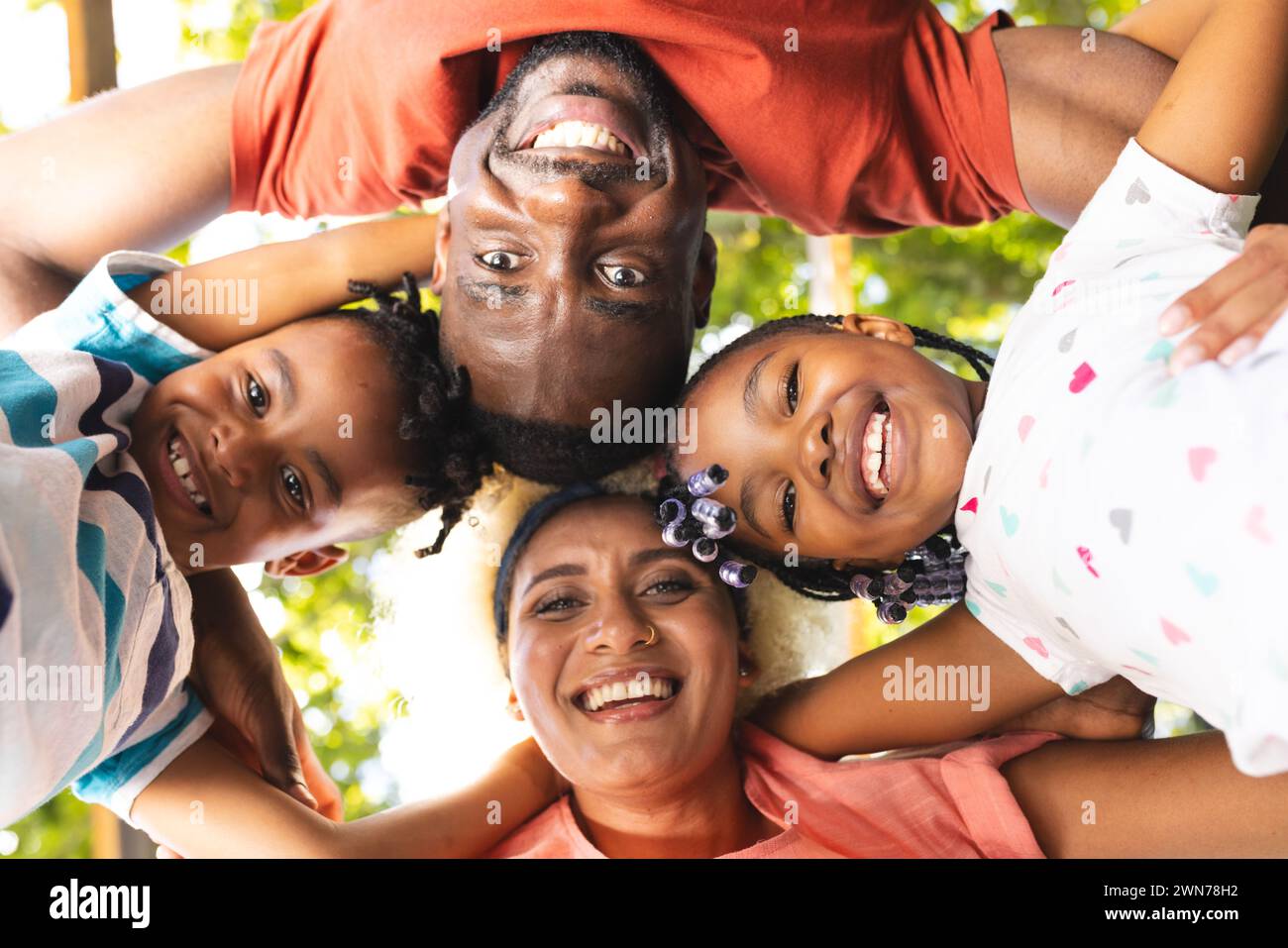 Diverse family forms a circle, smiling faces looking down at the camera Stock Photo