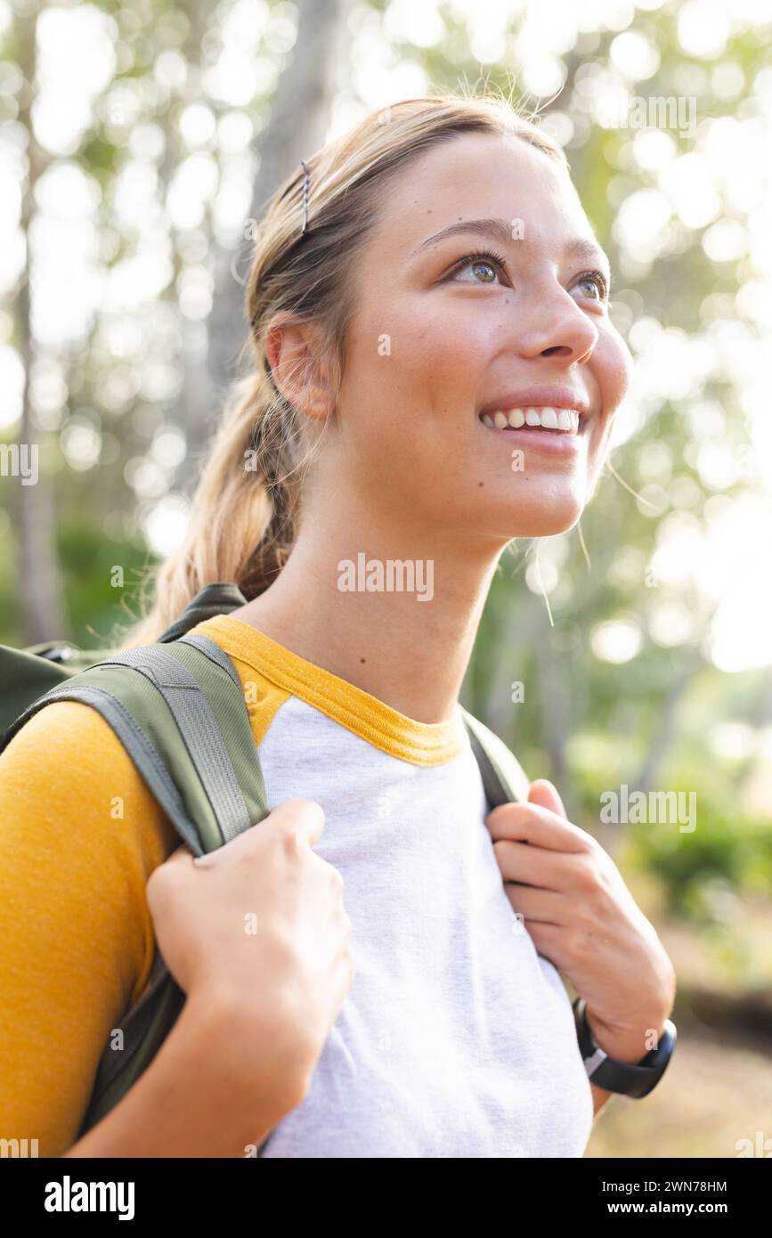 Young Caucasian woman with a backpack looks upwards with a smile Stock Photo