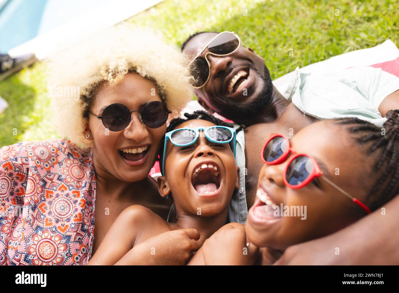 Family of four shares a sunny selfie moment outdoors. Stock Photo