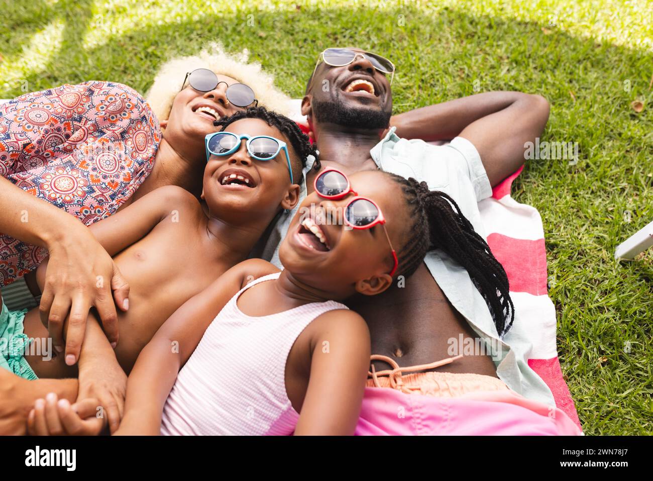 African American family enjoys a sunny day outdoors, lying on the grass with bright smiles Stock Photo