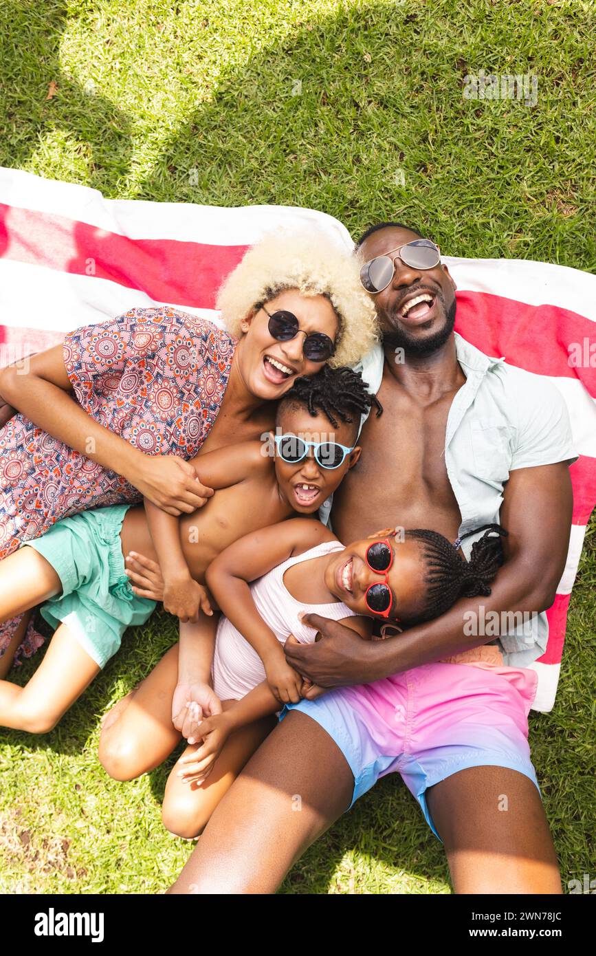 African American family enjoys a sunny day outdoors, lying on a colorful blanket Stock Photo