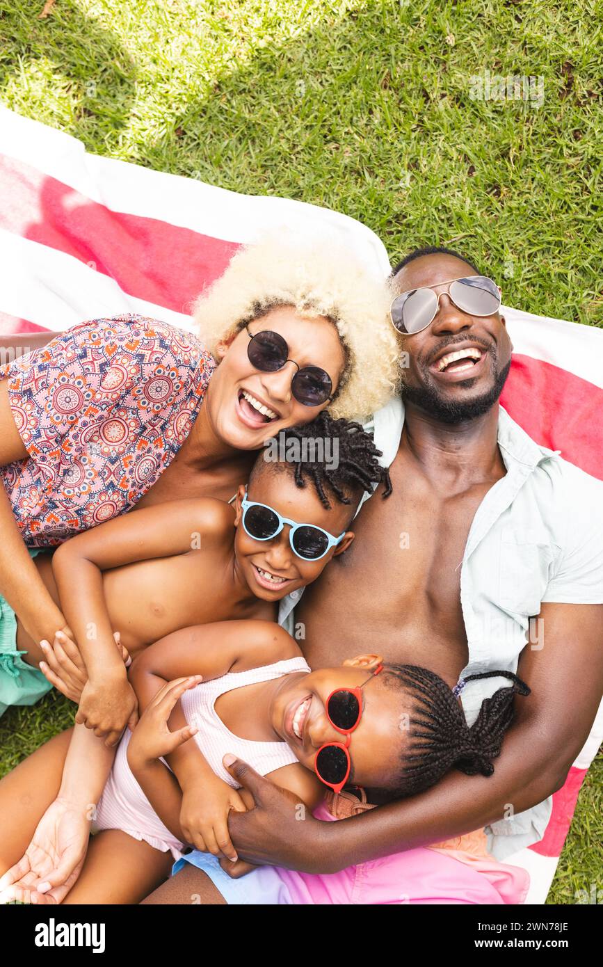 African American family enjoys a sunny day outdoors, lying on a striped blanket Stock Photo