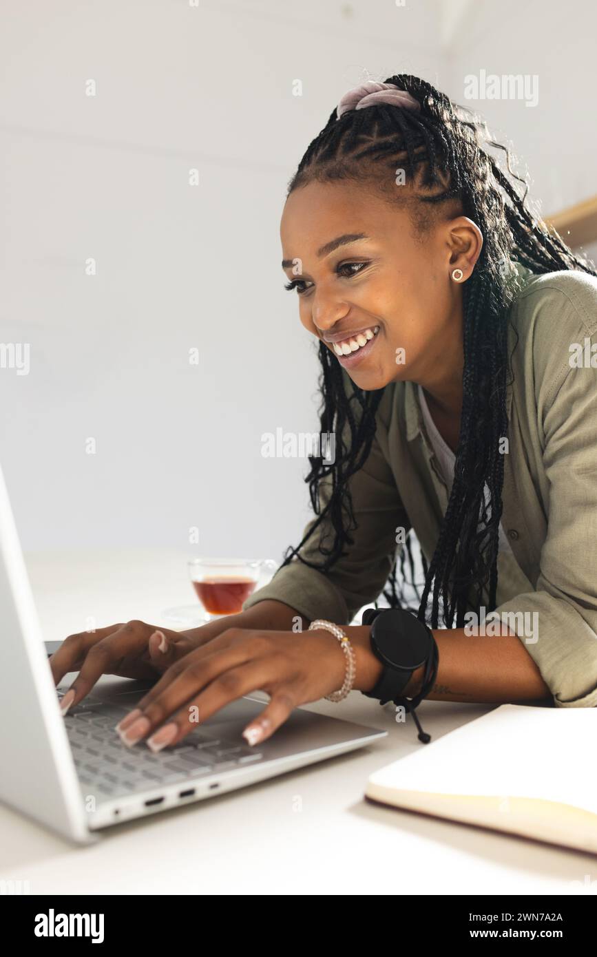 A young African American woman smiles while using a laptop Stock Photo ...
