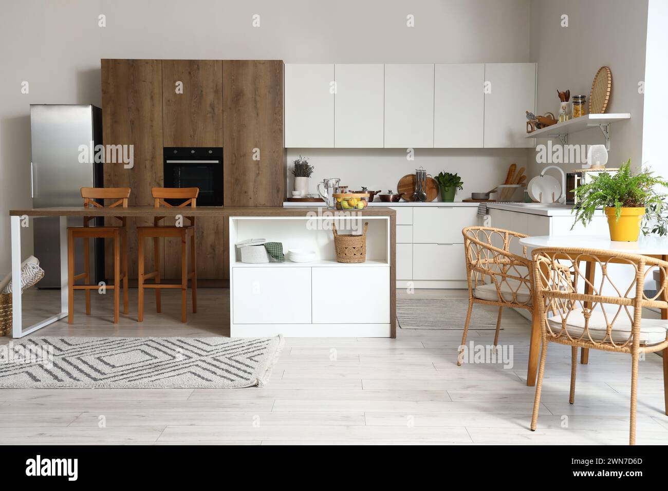 Interior of modern kitchen with white furniture and wooden island table ...
