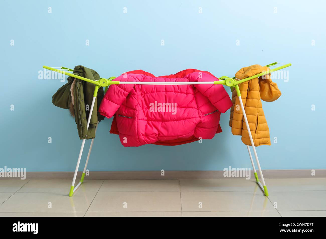 Clean puffer jackets hanging on dryer near blue wall Stock Photo Alamy