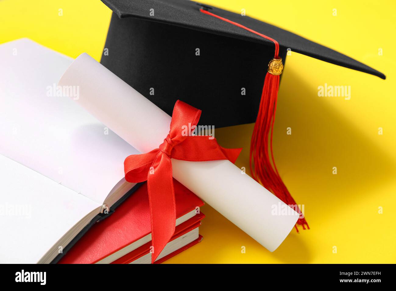 Graduation hat with diploma and notebooks on yellow background Stock ...