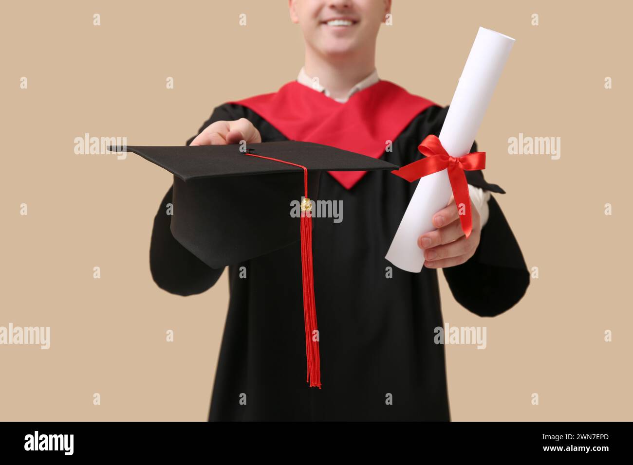 Male graduating student with mortar board and diploma on beige ...