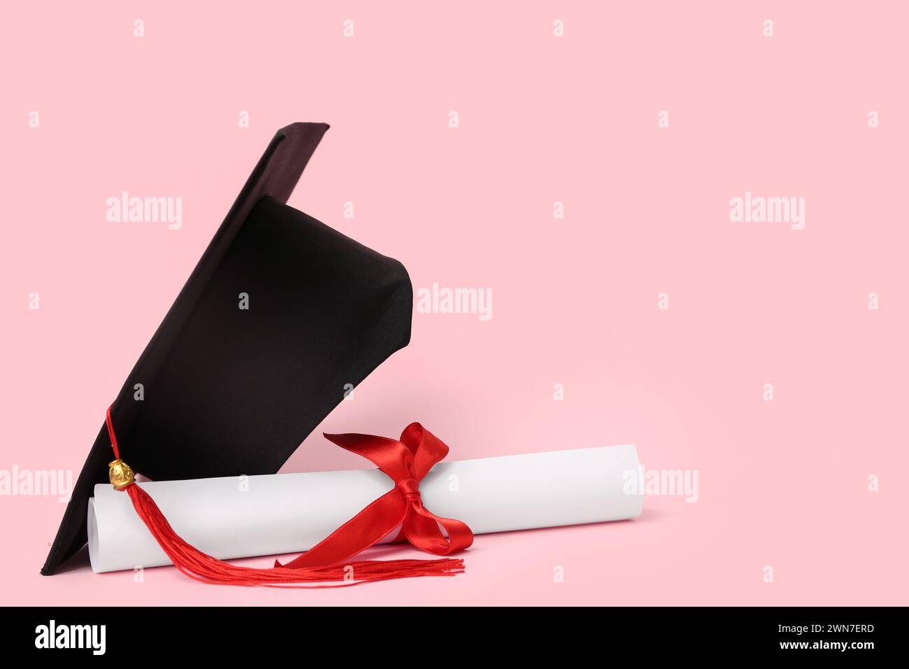 Mortar board and diploma on pink background Stock Photo - Alamy