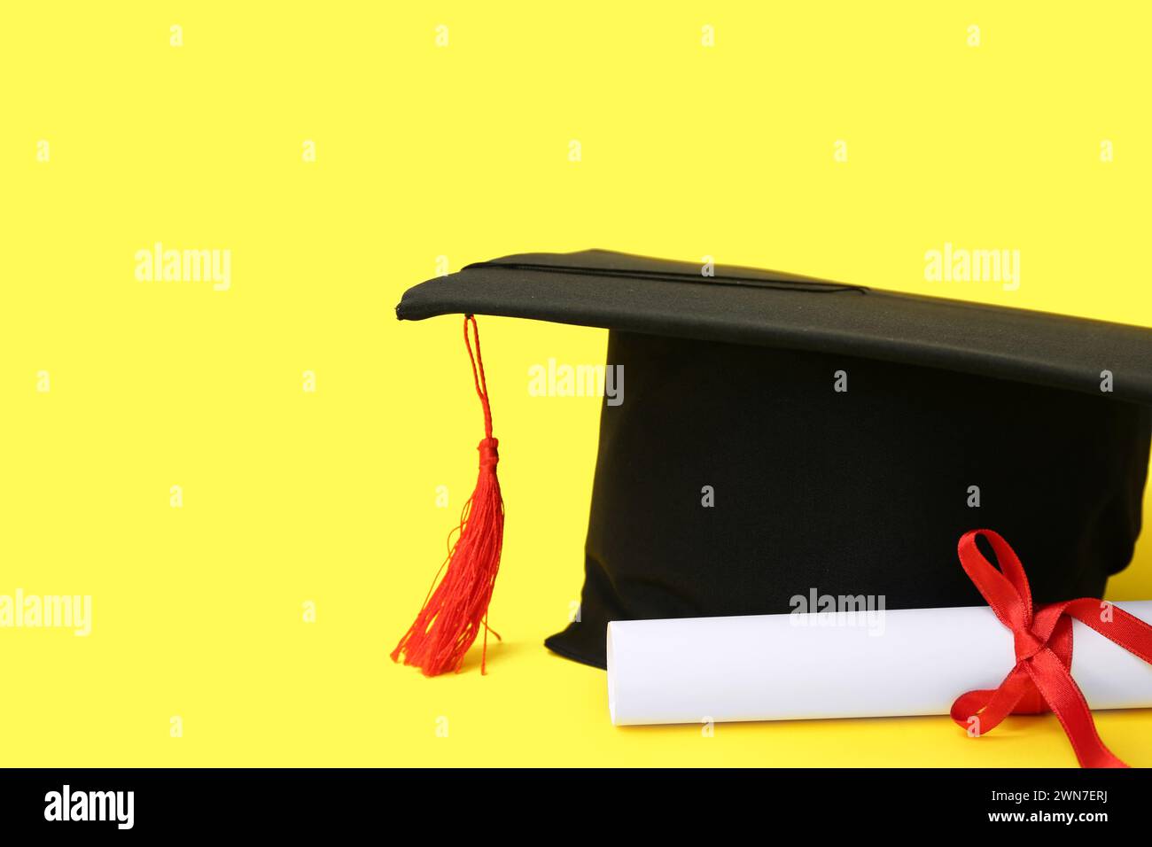 Mortar board and diploma on yellow background Stock Photo - Alamy