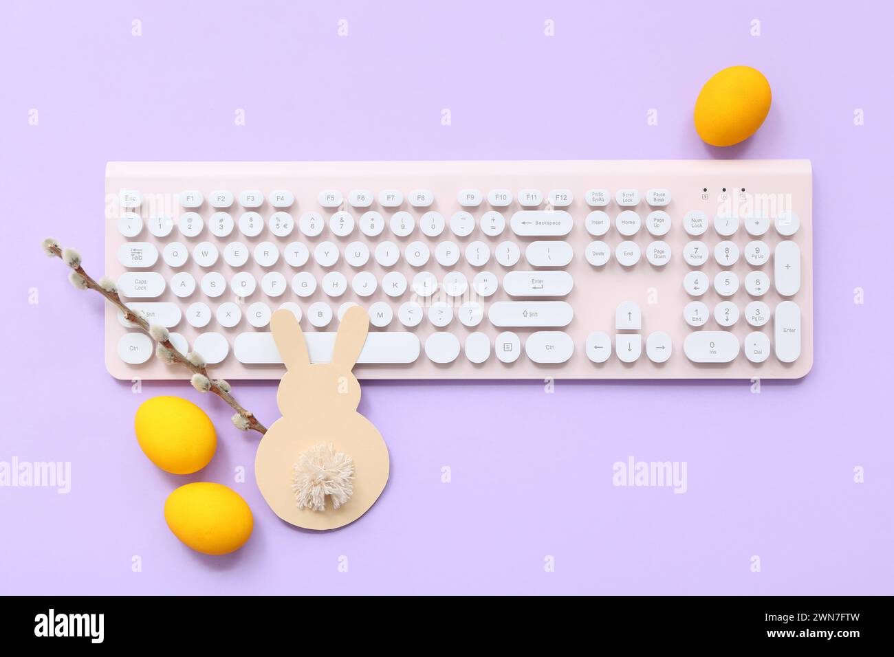 Easter eggs, willow branch and computer keyboard on purple background