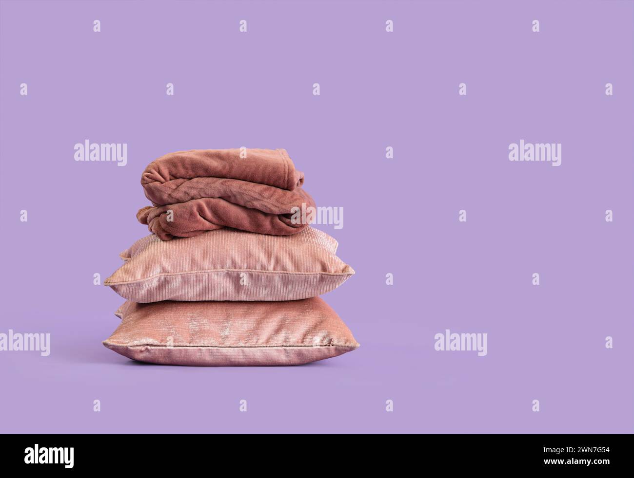 Stack of pillows with folded warm plaid on lilac background Stock Photo