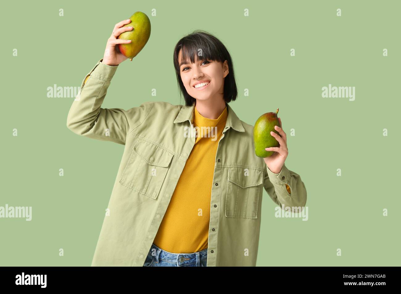 Beautiful young woman with ripe mangoes on green background Stock Photo ...