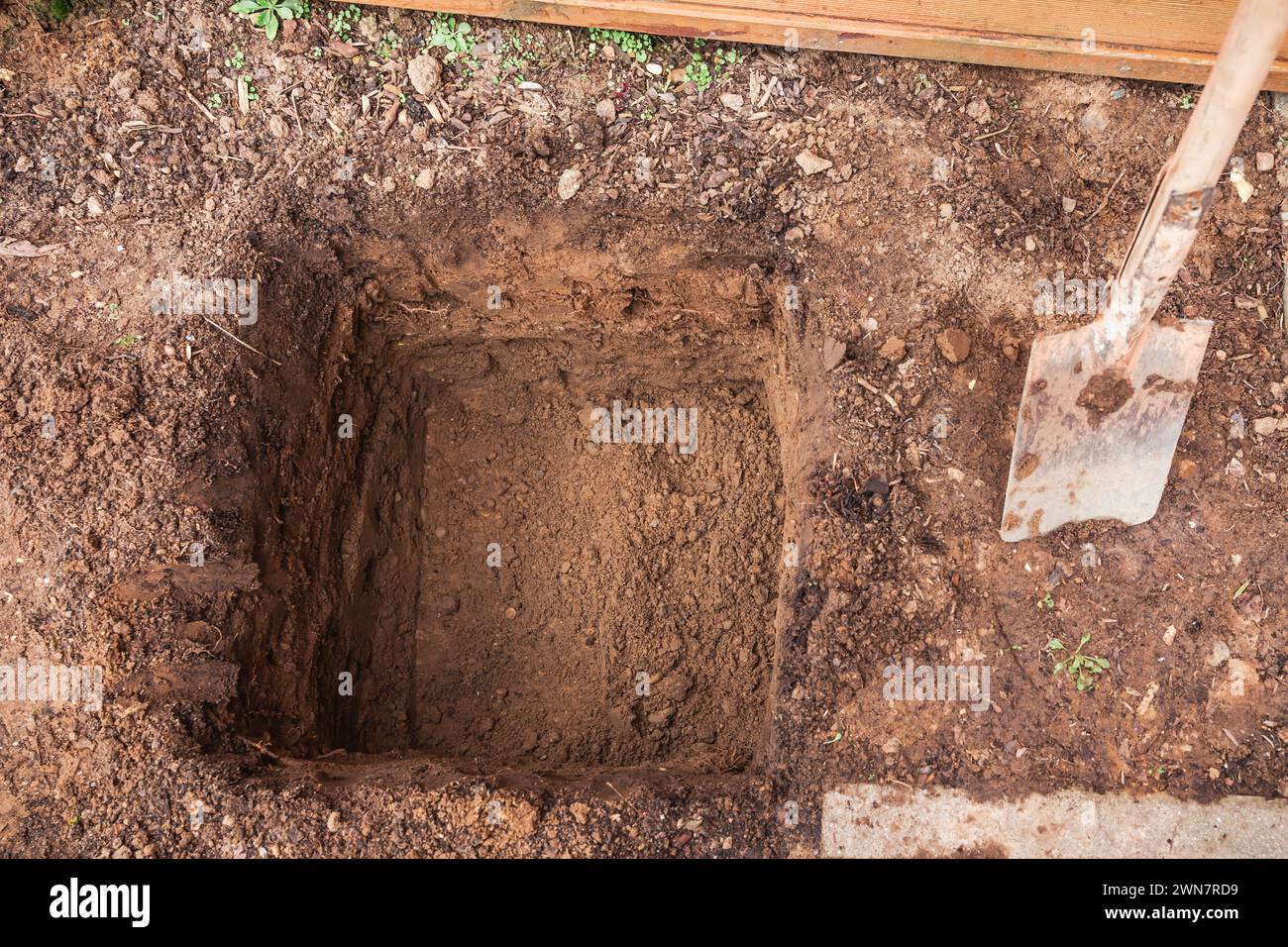 Hole in a soil, prepared for planting or construction, pit in a ground with shovel Stock Photo