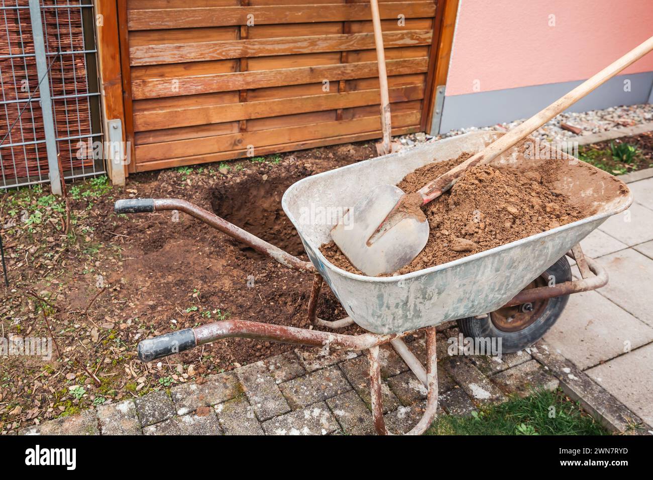 Wheelbarrow with soil and shovel, digging a hole for planting a tree or construction Stock Photo