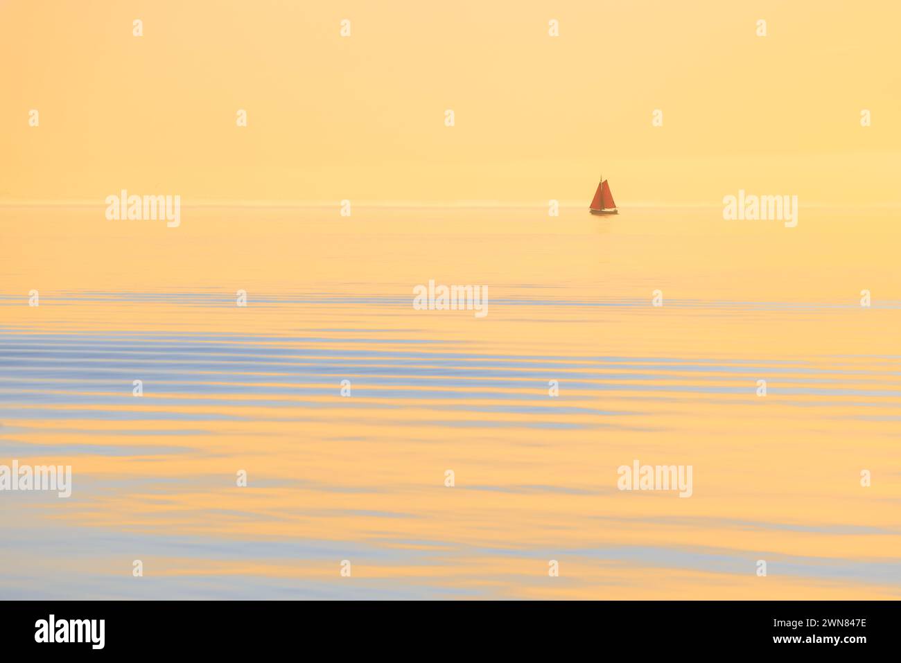 A Yacht on a calm ocean at sunset with golden light. The ship drifts ...
