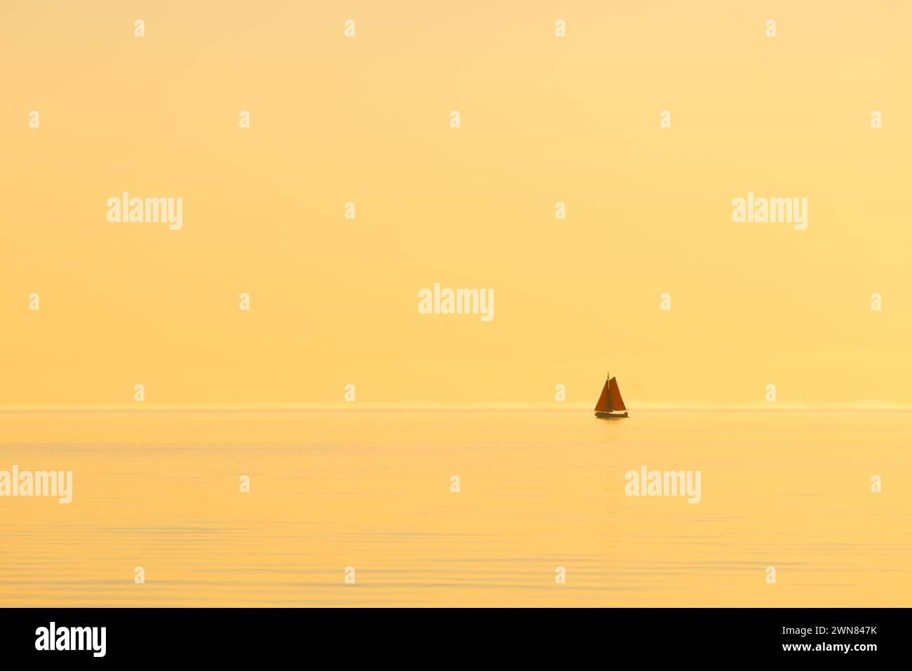 A Yacht on a calm ocean at sunset with golden light. The ship drifts ...