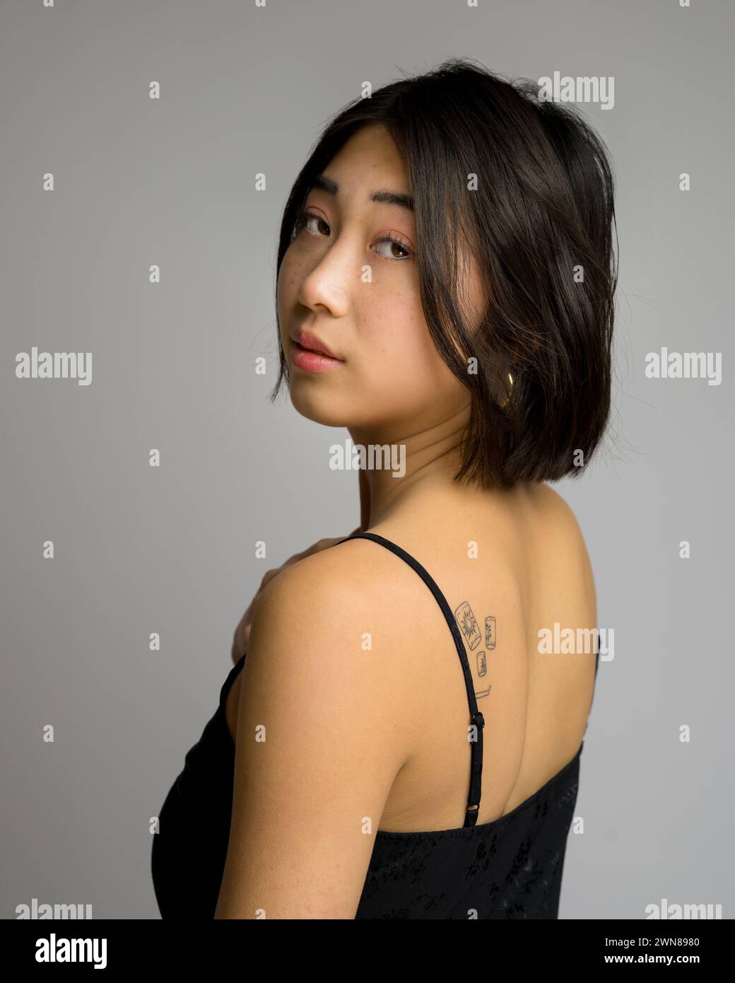 Profile Back Close Up of Young Asian Woman in Black Silk Blouse Top Spaghetti Straps Stock Photo